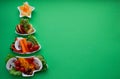 Plate in the form of a Christmas tree with vegetables, fruits, mushrooms and berries.Green background. The concept of vegetarian