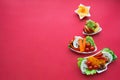 Plate in the form of a Christmas tree with vegetables, fruits, mushrooms and berries. Red background. The concept of vegetarian