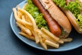 Plate with french fries and hot dogs on table, closeup Royalty Free Stock Photo