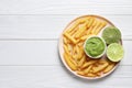 Plate with french fries, lime and avocado dip on white wooden table, top view. Space for text Royalty Free Stock Photo