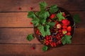 Plate with fresh berries (strawberries and currants) on dark wooden background. Royalty Free Stock Photo