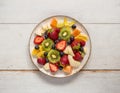 A plate of fresh fruit salad on a wooden table. Kiwi, oranges, blueberries, bananas. Healthy meal. vegetarian dish Royalty Free Stock Photo