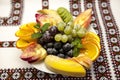 Plate with fresh fruits for the holidays: banana, grapes, orange, apple, kiwi, mint