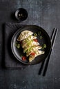 A plate with fresh gyoza dumpling on black plate and background with chopsticks