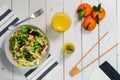 Plate of fresh Mediterranean salad with olive oil served with orange juice on a white wooden table Royalty Free Stock Photo