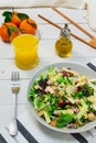 Plate of fresh Mediterranean salad with olive oil served with orange juice on a white wooden table Royalty Free Stock Photo