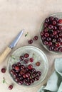 Plate of fresh red cherries and knife on beige background. Top view. Copy space. Royalty Free Stock Photo