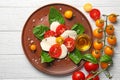 Plate with fresh sliced cherry tomatoes and mozzarella cheese on white wooden background Royalty Free Stock Photo