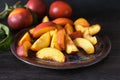 Plate with fresh sliced peaches on dark table Royalty Free Stock Photo