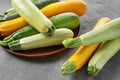 Plate with fresh zucchinis on grey table