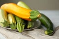 Plate with fresh zucchinis on white wooden table, closeup