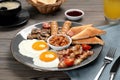 Plate of fried eggs, mushrooms, beans, tomatoes, bacon, sausages and toasts served on wooden table, closeup. Traditional English Royalty Free Stock Photo