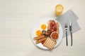 Plate of fried eggs, sausages, mushrooms, beans, bacon and toast on white wooden table, flat lay with space for text. Traditional Royalty Free Stock Photo