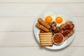 Plate of fried eggs, sausages, mushrooms, beans, bacon and toast on white wooden table, top view with space for text. Traditional Royalty Free Stock Photo