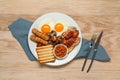Plate with fried eggs, sausages, mushrooms, beans, bacon and toast on wooden table, flat lay. Traditional English breakfast Royalty Free Stock Photo