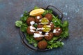 Plate of fried falafel balls served with fresh green cilantro and lemon, top view on rustic concrete background