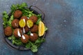 Plate of fried falafel balls served with fresh green cilantro and lemon top view on rustic concrete background