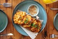 A plate of fried food with a side of sauce sits on a wooden table Royalty Free Stock Photo