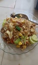 A plate of fried rice with tofu, mustard greens, cabbage, tomato, cucumber