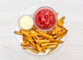 Plate with fries potato, ketchup and mayonnaise on the table. Top view Royalty Free Stock Photo