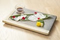 Plate of fugu sashimi garnished with edible flowers on wooden background