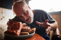 A plate full of barbecues and a man looking very excited to eat it Royalty Free Stock Photo