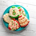 A plate full of colourful ugly Christmas sweater cookies on a wooden table.