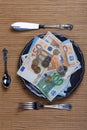 A plate full of money ready to be eaten with cutlery