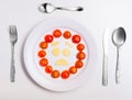 Plate with funny emoticons made from food with cutlery on white