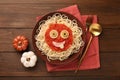 Plate with funny monster made of tasty pasta served on wooden table, flat lay. Halloween food Royalty Free Stock Photo