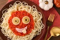 Plate with funny monster made of tasty pasta served on wooden table, flat lay. Halloween food Royalty Free Stock Photo