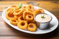 plate of golden onion rings with ketchup dip