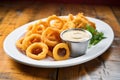 plate of golden onion rings with ketchup dip