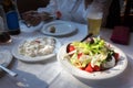 A plate of a Greek salad and tzatziki on a table, indoors.