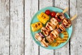 Summer BBQ or picnic food with grilled chicken kabobs, corn, and pineapple, top view on white wood Royalty Free Stock Photo