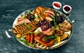 Plate of grilled meat - lamb, sausages, ribs, sauce, grilled vegetables. Royalty Free Stock Photo