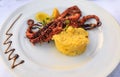 Plate of grilled octopus and polenta, decorated with balsamic vinegar and fresh herbs at a restaurant in Montenegro