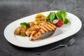 Plate of grilled salmon steak with vegetables on dark stone table Royalty Free Stock Photo