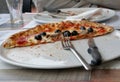 A plate with a half of pizza with cutlery and a another plate. Royalty Free Stock Photo