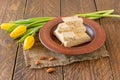 Plate with halva from sunflower seeds and yellow tulips on wooden table