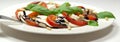 Plate of healthy classic delicious caprese salad with ripe tomatoes and mozzarella cheese with fresh basil leaves on white wooden Royalty Free Stock Photo