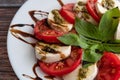 Plate of healthy classic delicious caprese salad with tomatoes and mozzarella cheese with fresh basil leaves on light linen