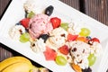 Plate of healthy fresh fruit salad with ice cream on the wooden background. Top view Royalty Free Stock Photo