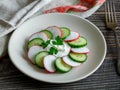 Plate with healthy spring vegetarian salad with radish, cucumber and parsley with sour cream. top view on wooden Royalty Free Stock Photo