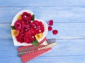 plate of heart flowers roses, fork, knife greeting on a blue wooden background, beads Royalty Free Stock Photo