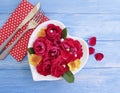 plate of heart flowers roses, fork, knife on a blue wooden background, beads Royalty Free Stock Photo