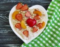 Plate of heart oatmeal porridge, strawberry, apricot on a wooden background Royalty Free Stock Photo