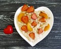 Plate heart oatmeal porridge, strawberry, apricot on a wooden background Royalty Free Stock Photo