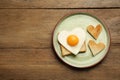 Plate with heart shaped fried egg and toasts on wooden table, top view. Space for text Royalty Free Stock Photo