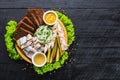 Plate with herring, lard and vegetables on wooden background